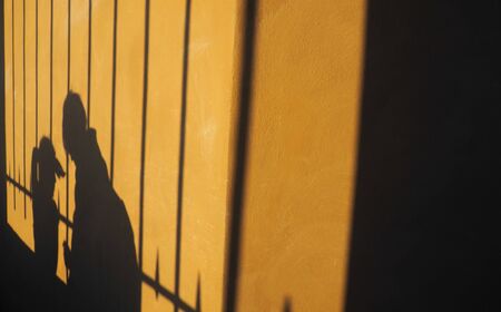 Shadow on the wall of a man and a woman looking down and facing each otherの写真素材