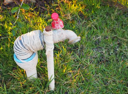 Dirty old faucet on green grass backourundの写真素材