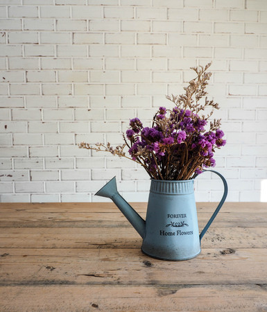 Artificial flower, home decoration, on wooden table and white brick wall.の写真素材
