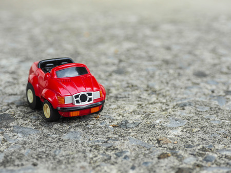 A red toy car park on rough cement road.の写真素材