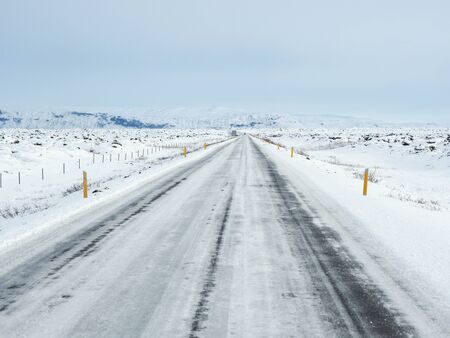 Winter road with mountain on the side of the road covered with snowの写真素材