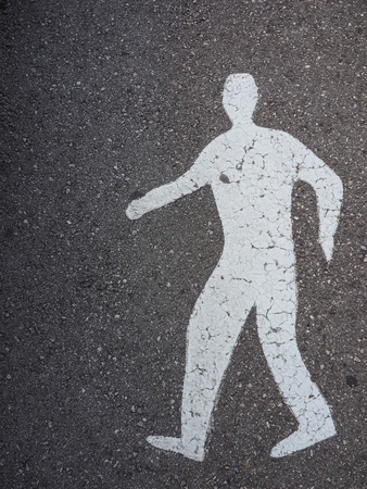 Old asphalt texture background with white man road sign, top viewの写真素材