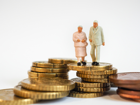 Miniature senior couple stand on pile of Euro coins. Retirement planning concept.の写真素材