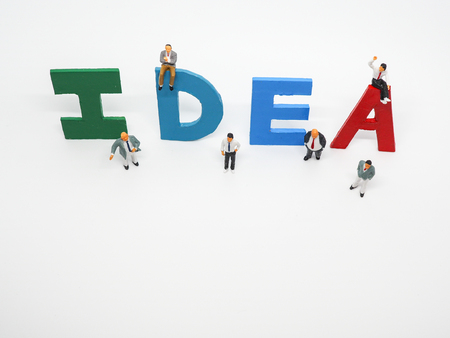 Miniature bussinessman with IDEA word letters on white background, business conceptの写真素材