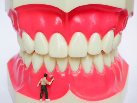 Miniature worker on plastic teeth of removable denture. Dental health concept