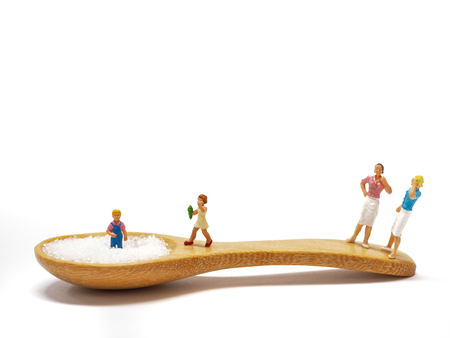 Miniature little children standing on a wooden spoon and thinking of sugar, diet, fat and diabetes. Health care conceptの写真素材