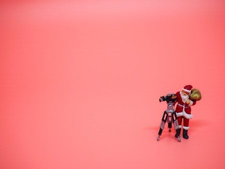 Miniature santa claus with VDO camera on pink background. Christmas and Happy New Year conceptの写真素材
