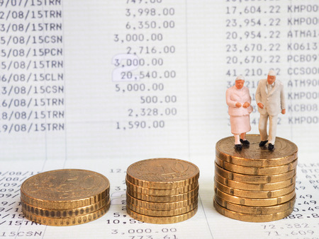 Miniature senior couple stand on pile of Euro coins. Retirement planning concept.の写真素材