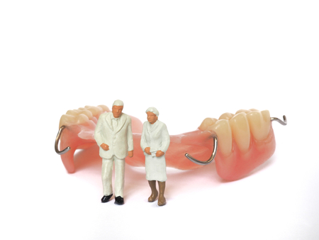 Miniature elderly couple standing on removable denture, on white background. Dental health conceptの写真素材
