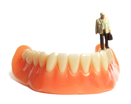 Miniature elderly standing on removable denture, on white background. Dental health concept.の写真素材