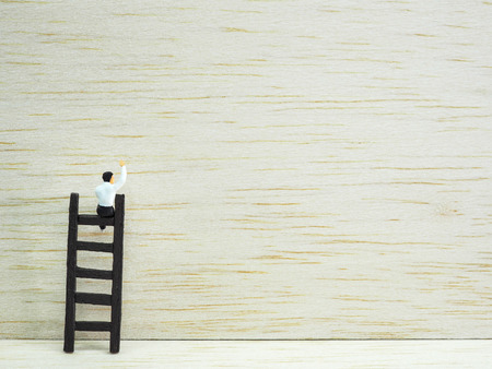Miniature businessman standing on the stair on wooden background. Business  conceptの写真素材