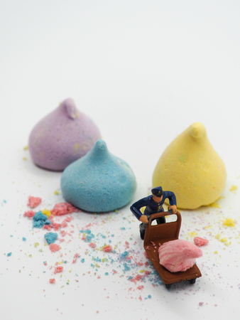 Miniature man with trolly and colorful merengue on white background, selective focus. sweet dessertの写真素材