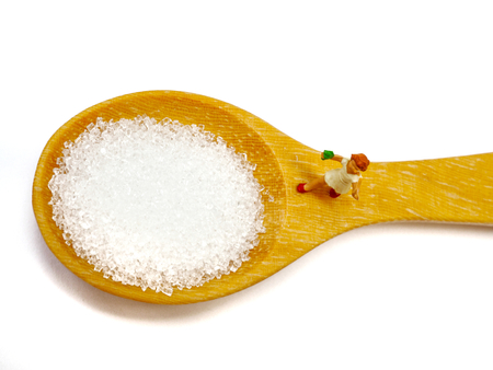 Miniature little child standing on a wooden spoon and thinking of sugar, diet, fat and diabetes. Health care concept.の写真素材