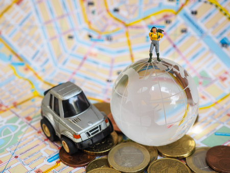 Miniature traveller or backpacker stand on globe of glass, Euro coins and map. Travelling concept.の写真素材