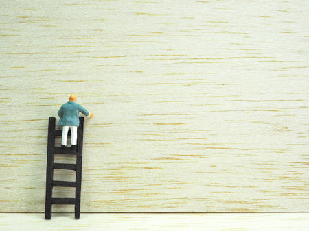 Miniature businessman standing on the stair on wooden background. Business  conceptの写真素材