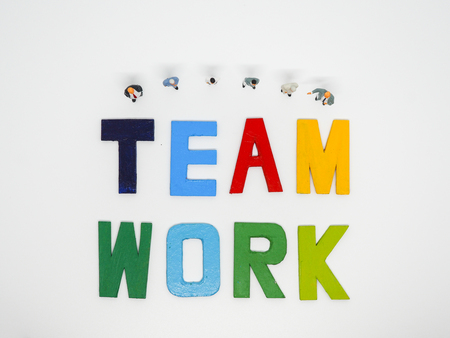 Miniature bussinessman with TEAMWORK word letters on white background, business concept.の写真素材