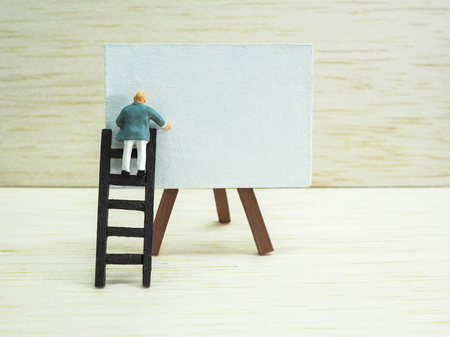 Miniature businessman standing on the stair, in front of an drawing frame on wooden background. Business  conceptの写真素材