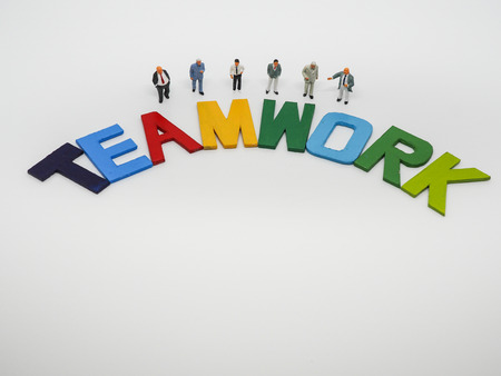 Miniature bussinessman with TEAMWORK word letters on white background, business concept.の写真素材
