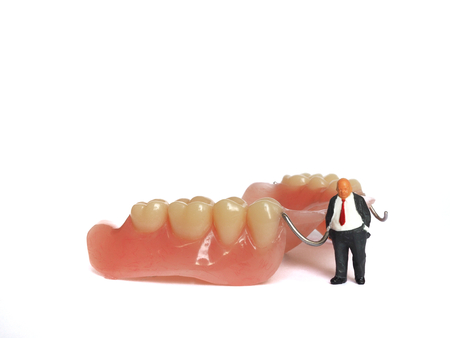 Miniature elderly standing on removable denture, on white background. Dental health concept.の写真素材