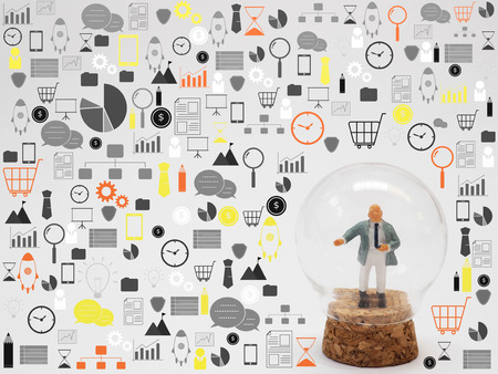 Miniature businessman standing in glass bottle surrounded by business icons on white background. Business and finance conceptの写真素材