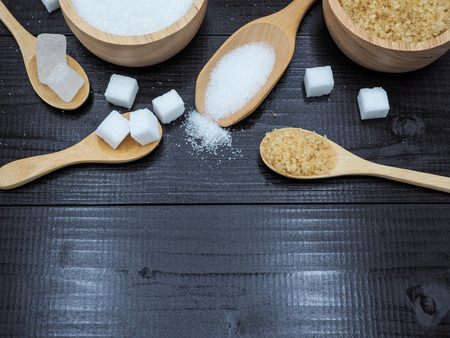 Wooden bowl and spoon with sugar cube on dark wood background.の写真素材