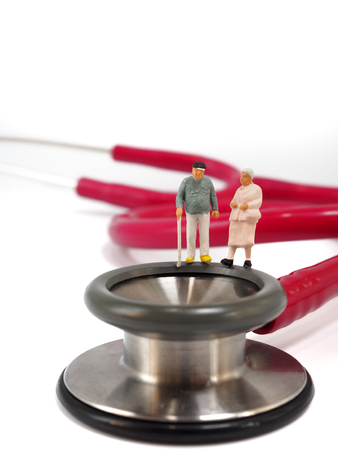 Miniature senior couple, small figures, standing on stethoscope. Health care and healthy lifestyle concept.の写真素材