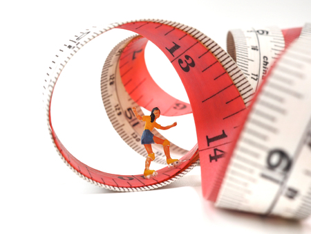 Miniature woman skating on measuring tape, thinking of weight loss and slim body. Healthy lifestyle concept.の写真素材