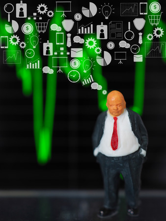 Miniature businessman standing in front of stock graph  with white business icon. Business conceptの写真素材