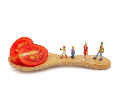 Miniature children standing on fresh grape or cherry tomato with wooden spoon, thinking of healthy, nutrient and clean food. Healthy lifestyle concept. white background.の写真素材