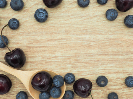 Fresh cherry and blueberry with spoon on wooden background. Healthy food and diet.の写真素材