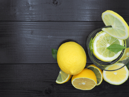 Fresh lemon juice in small bowl and lemon slice on dark wood backgroundの写真素材