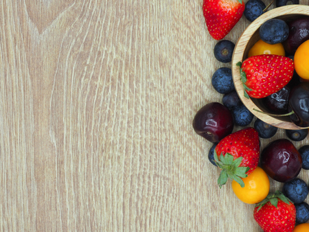 Fresh summer fruits, Cherry, strawberry, cape gooseberry and blueberry in wooden plate isolated on white background.の写真素材