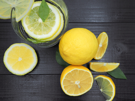Fresh lemon juice in small bowl and lemon slice on dark wood backgroundの写真素材
