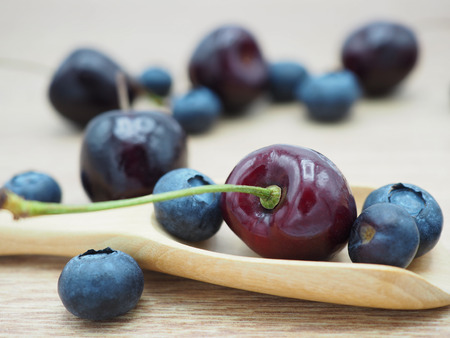 Fresh cherry and blueberry with spoon on wooden background. Healthy food and diet.の写真素材