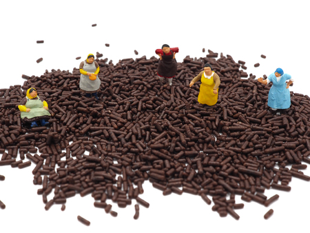 Miniature fat women on chocolate sprinkles on white background. Diet, fat and weight loss concept.の写真素材