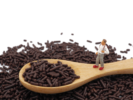 Miniature teenagers on chocolate sprinkles on white background. Diet, fat and weight loss concept.の写真素材
