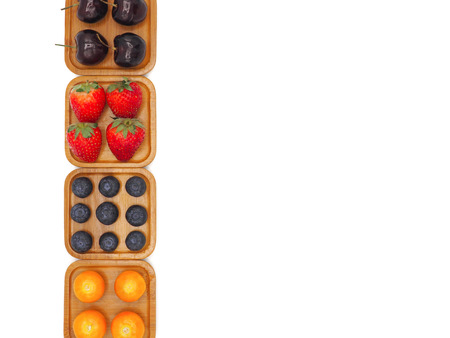 Fresh summer fruits, Cherry, strawberry, cape gooseberry and blueberry in wooden plate isolated on white background.の写真素材