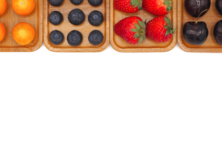 Fresh summer fruits, Cherry, strawberry, cape gooseberry and blueberry in wooden plate isolated on white background.の写真素材