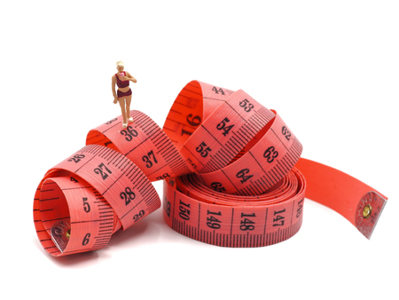 Miniature slim woman with measuring tape on white background,  Healthy lifestyle concept.の写真素材