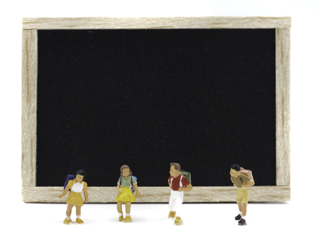Miniature children standing in front of a blackboard on white background. Back to school concept.の写真素材