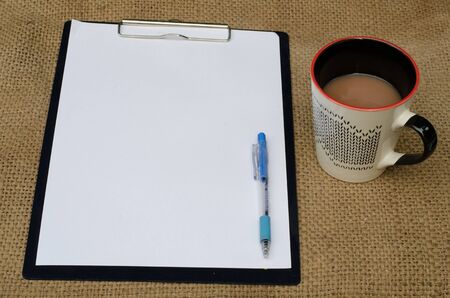 The note book and paper writing set with a cup of coffee ,on sackcloth backgroundの写真素材