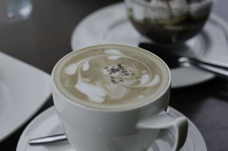 soft focus on foam of  cappuccino in a cup on the table with a blur dessert backgroundの写真素材
