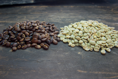 raw and roasted coffee beans on wood tableの写真素材