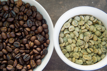 raw and roasted coffee beans in white cupの写真素材