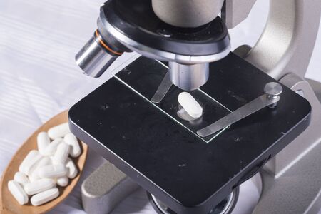 White pill on microscopeの写真素材