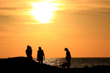 Silhouette of people in the evening at the beach.の写真素材