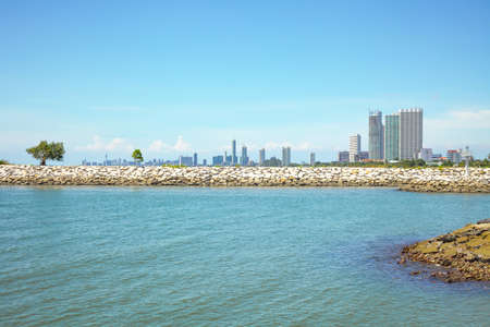 Rocks jutting out into the sea wave and buildingの写真素材