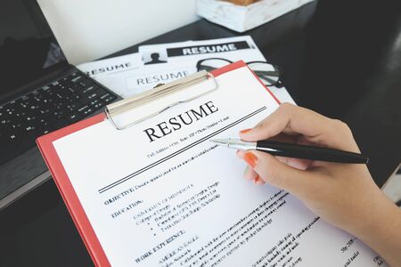 Closeup of resume with pen. computer laptop and glasses on the wooder table