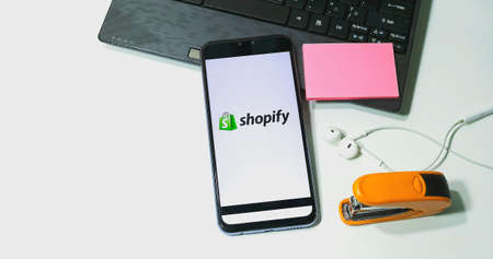 CHIANG MAI, THAILAND - May 18,2020: Flat lay of workspace desk and Smart Phone with Shopify...