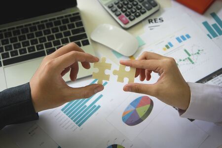 Two hands connect pieces of the puzzle against on table office. Business concept idea, promotion,...
